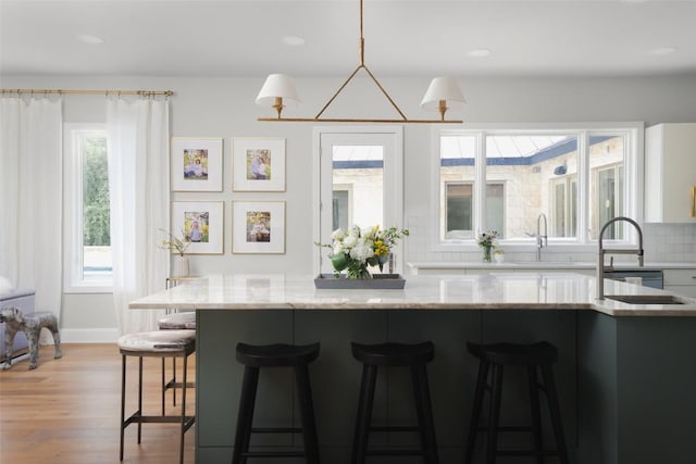 114 Medalist St, Lakeway, TX 78734 - kitchen featuring light wood-type flooring, a kitchen breakfast bar, light stone counters, backsplash, and recessed lighting