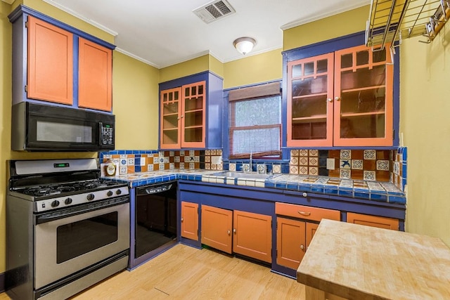 2834 Pearl St, Austin, TX 78705 - kitchen with black appliances, backsplash, light wood-type flooring, crown molding, and glass insert cabinets