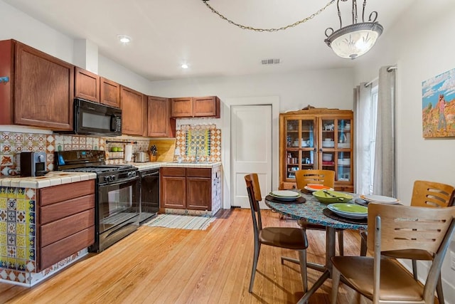 2834 Pearl St, Austin, TX 78705 - kitchen featuring black appliances, tasteful backsplash, tile countertops, light wood-style flooring, and brown cabinetry