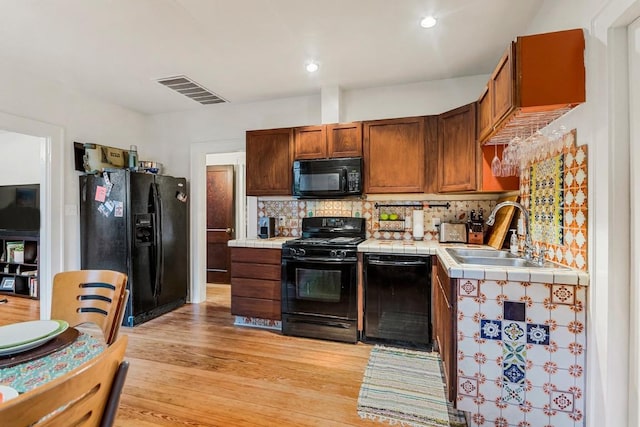 2834 Pearl St, Austin, TX 78705 - kitchen featuring black appliances, tile countertops, decorative backsplash, light wood-style floors, and recessed lighting