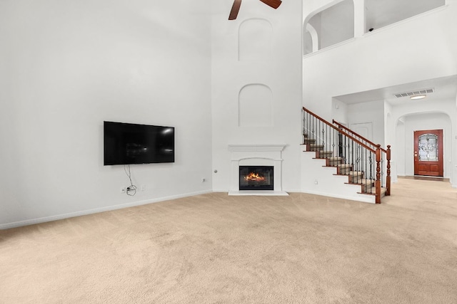 204 Lake Livingston Dr, Georgetown, TX 78628 - unfurnished living room with carpet flooring, a high ceiling, ceiling fan, arched walkways, and a glass covered fireplace