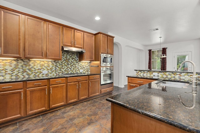204 Lake Livingston Dr, Georgetown, TX 78628 - kitchen featuring appliances with stainless steel finishes, brown cabinets, arched walkways, tasteful backsplash, and recessed lighting