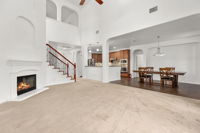 204 Lake Livingston Dr, Georgetown, TX 78628 - living room with arched walkways, dark colored carpet, ceiling fan, a glass covered fireplace, and a high ceiling