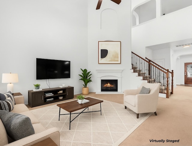 204 Lake Livingston Dr, Georgetown, TX 78628 - carpeted living room featuring arched walkways, a towering ceiling, stairway, a warm lit fireplace, and ceiling fan