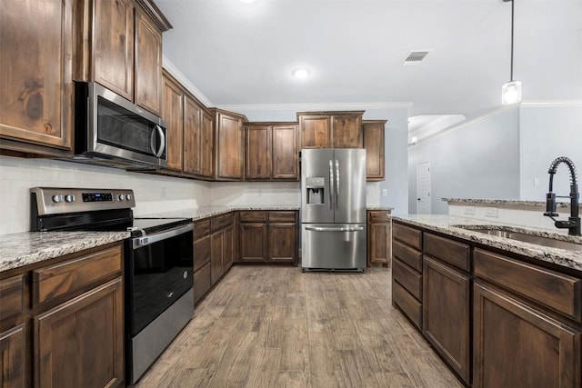 2660 Cowgirl Trl, Belton, TX 76513 - kitchen with appliances with stainless steel finishes, wood finished floors, decorative backsplash, light stone countertops, and ornamental molding