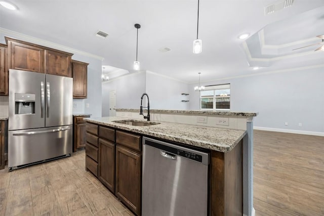 2660 Cowgirl Trl, Belton, TX 76513 - kitchen with appliances with stainless steel finishes, crown molding, an island with sink, a chandelier, and light wood-style floors