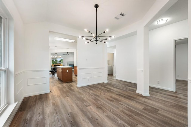 608 Haleys Cv, Leander, TX 78641 - unfurnished living room featuring a chandelier, dark wood-type flooring, a wainscoted wall, and lofted ceiling
