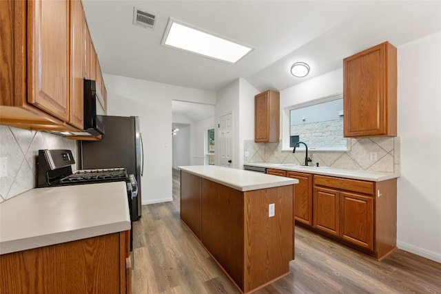 608 Haleys Cv, Leander, TX 78641 - kitchen with a center island, black microwave, light countertops, decorative backsplash, and brown cabinetry