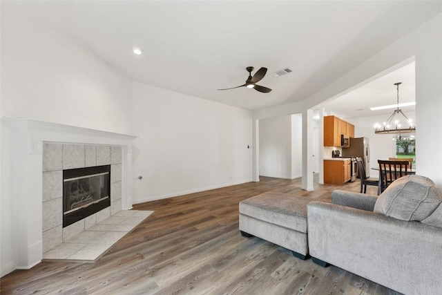608 Haleys Cv, Leander, TX 78641 - living room with ceiling fan, a tile fireplace, wood finished floors, a chandelier, and vaulted ceiling