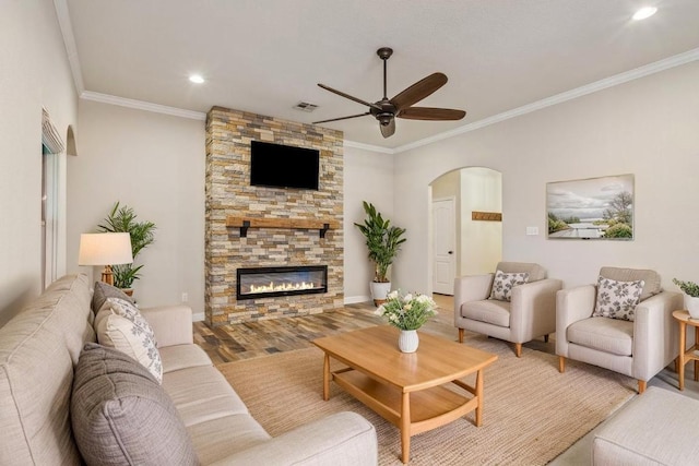 5012 Jeanine Dr, Temple, TX 76502 - living room with arched walkways, a ceiling fan, ornamental molding, a stone fireplace, and light wood-type flooring