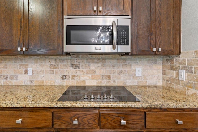 5012 Jeanine Dr, Temple, TX 76502 - kitchen featuring stainless steel microwave, black electric stovetop, backsplash, and dark brown cabinets
