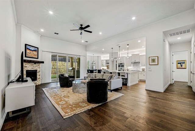 120 Delfino Pl, Horseshoe Bay, TX 78657 - living room featuring a ceiling fan, ornamental molding, dark wood-type flooring, a stone fireplace, and recessed lighting