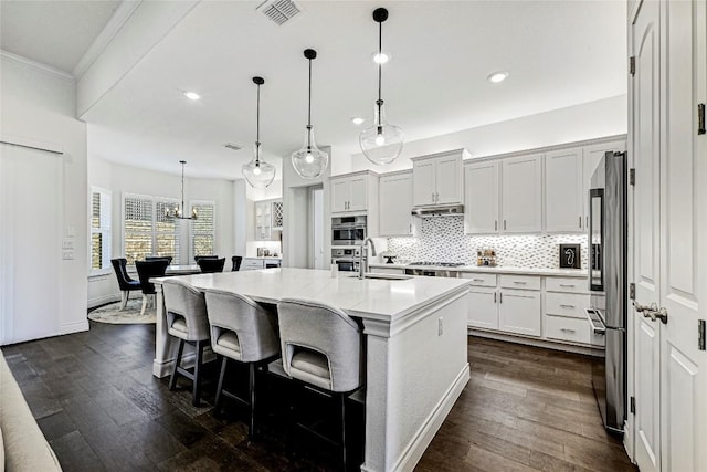 120 Delfino Pl, Horseshoe Bay, TX 78657 - kitchen with recessed lighting, dark wood-style floors, tasteful backsplash, a kitchen bar, and appliances with stainless steel finishes
