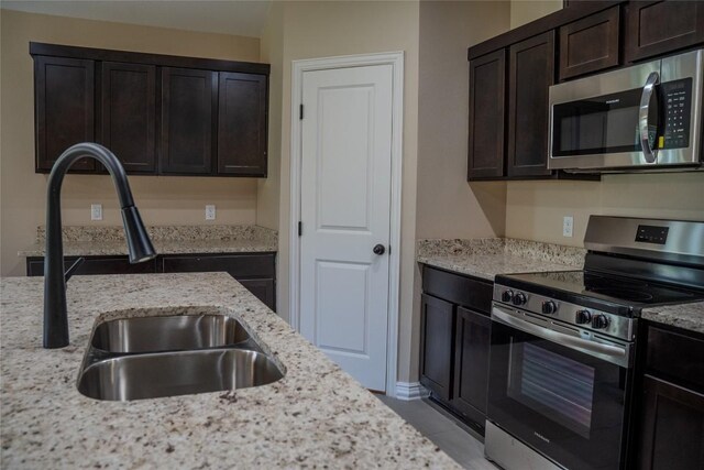 2230 Mc Arthur Ave, Kingsland, TX 78639 - kitchen featuring appliances with stainless steel finishes, light stone countertops, dark brown cabinets, and light tile patterned floors