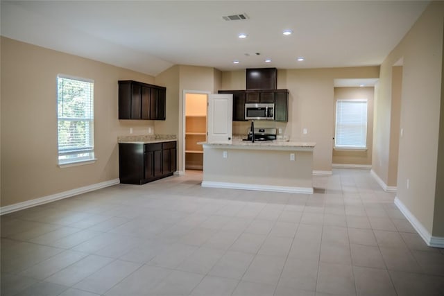 2230 Mc Arthur Ave, Kingsland, TX 78639 - kitchen with stainless steel microwave, stove, an island with sink, dark brown cabinets, and light stone countertops