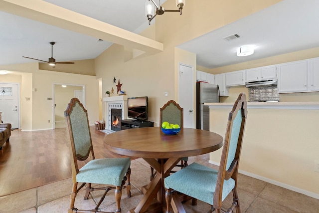 3008 Siskin Dr, Austin, TX 78745 - dining room with a lit fireplace, ceiling fan, and high vaulted ceiling