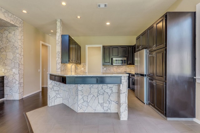 146 Double Eagle Dr, Austin, TX 78738 - kitchen featuring stainless steel appliances, a peninsula, backsplash, light stone counters, and recessed lighting