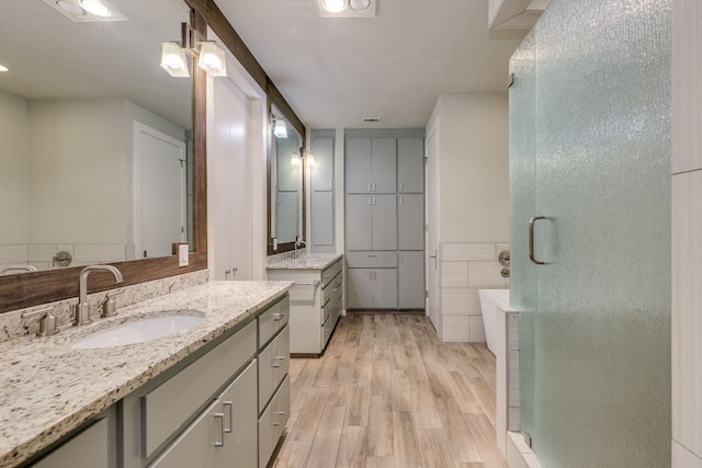 146 Double Eagle Dr, Austin, TX 78738 - bathroom with two vanities, wood finished floors, a stall shower, and a bath