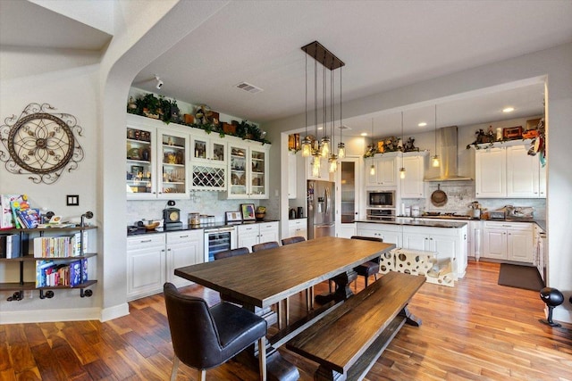 1915 Los Santos Dr, San Marcos, TX 78666 - dining space featuring beverage cooler, light wood-style flooring, arched walkways, recessed lighting, and bar area
