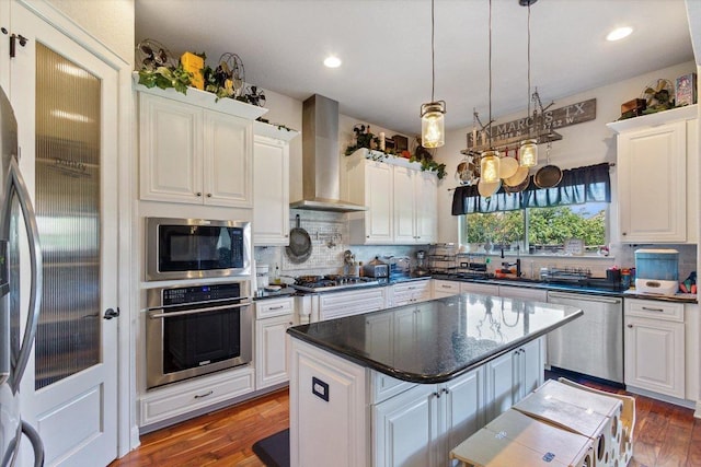 1915 Los Santos Dr, San Marcos, TX 78666 - kitchen featuring stainless steel appliances, wall chimney exhaust hood, white cabinets, tasteful backsplash, and wood finished floors