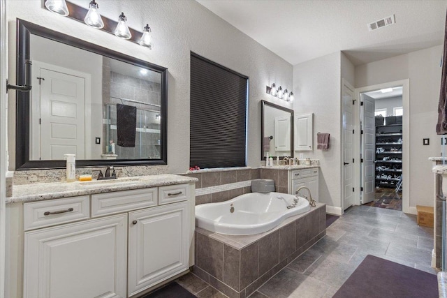 1915 Los Santos Dr, San Marcos, TX 78666 - full bathroom with a stall shower, two vanities, a garden tub, and a walk in closet
