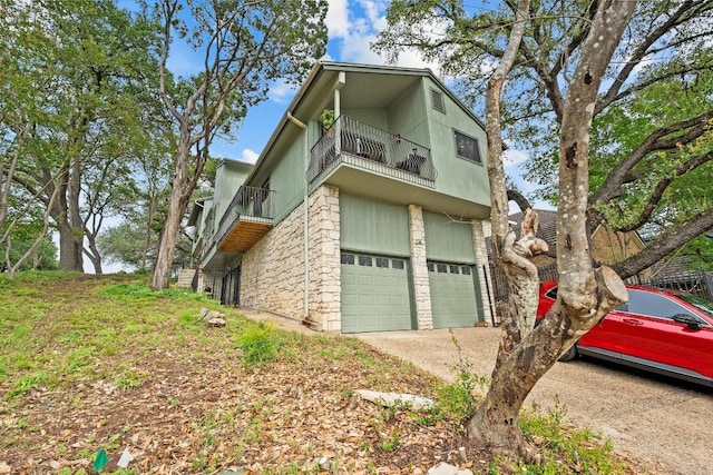 6033 Mount Bonnell Cv, Austin, TX 78731 - view of side of property with a balcony, an attached garage, driveway, and stone siding