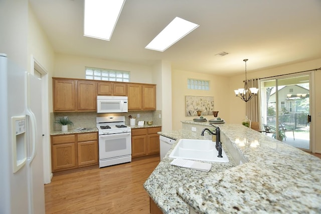 101 Bass St, Georgetown, TX 78633 - kitchen featuring white appliances, light wood-type flooring, tasteful backsplash, a chandelier, and pendant lighting
