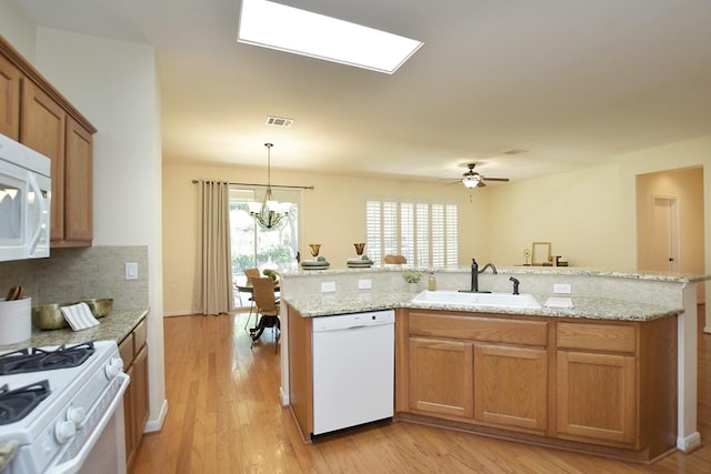 101 Bass St, Georgetown, TX 78633 - kitchen featuring white appliances, decorative backsplash, light wood-style flooring, a chandelier, and light stone counters