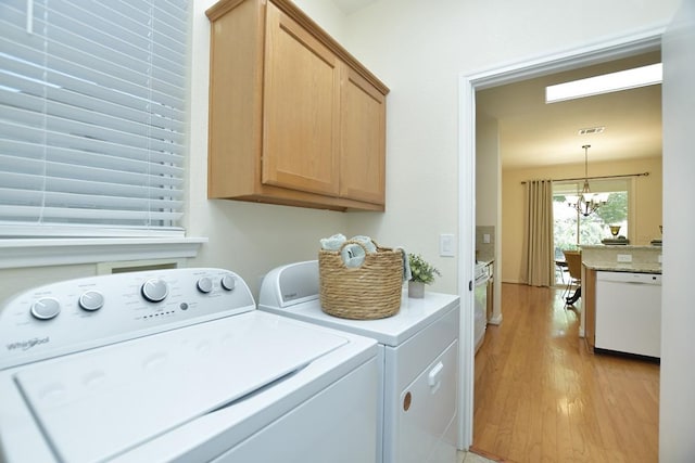 101 Bass St, Georgetown, TX 78633 - laundry area featuring washing machine and dryer, cabinet space, light wood-type flooring, and a chandelier