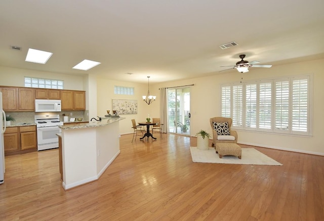 101 Bass St, Georgetown, TX 78633 - kitchen featuring white appliances, light wood-style floors, a peninsula, a chandelier, and backsplash