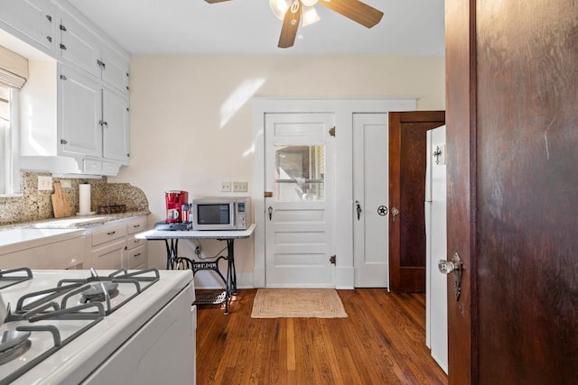 306 S Market St, Flatonia, TX 78941 - kitchen featuring stainless steel microwave, white gas stove, a ceiling fan, dark wood-type flooring, and white cabinets