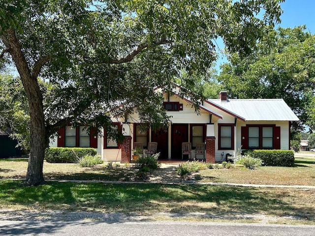 306 S Market St, Flatonia, TX 78941 - view of front of home featuring covered porch, a chimney, a front lawn, and brick siding