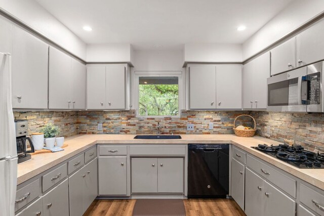 8604 Granada Hills Dr, Austin, TX 78737 - kitchen with black appliances, light wood-style floors, light countertops, backsplash, and recessed lighting