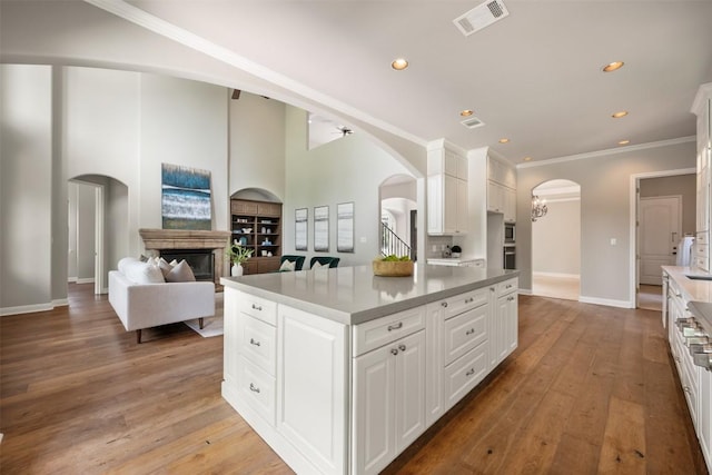 27 Autumn Oaks Dr, The Hills, TX 78738 - kitchen with arched walkways, white cabinets, ornamental molding, a kitchen island, and recessed lighting