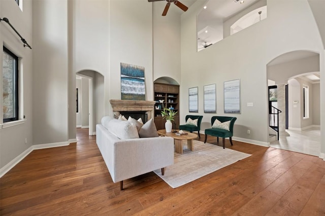 27 Autumn Oaks Dr, The Hills, TX 78738 - living room featuring a ceiling fan, a high ceiling, hardwood / wood-style floors, arched walkways, and a fireplace