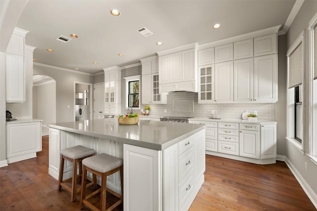 27 Autumn Oaks Dr, The Hills, TX 78738 - kitchen with arched walkways, crown molding, backsplash, recessed lighting, and glass insert cabinets