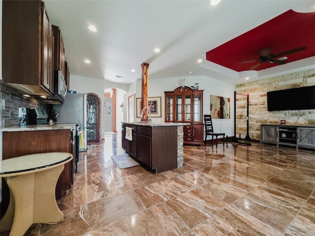 204 Matthew Cv, Bastrop, TX 78602 - kitchen featuring arched walkways, stainless steel microwave, a ceiling fan, dark brown cabinetry, and range with electric cooktop