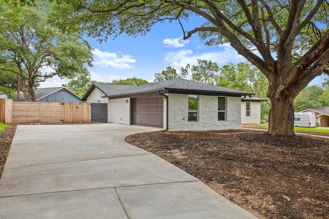 11615 February Dr, Austin, TX 78753 - view of front of home with concrete driveway, a garage, stone siding, and a shingled roof