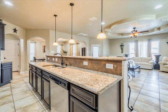 913 Overcup Dr, San Marcos, TX 78666 - kitchen featuring stainless steel dishwasher, arched walkways, light tile patterned flooring, ceiling fan, and a center island with sink