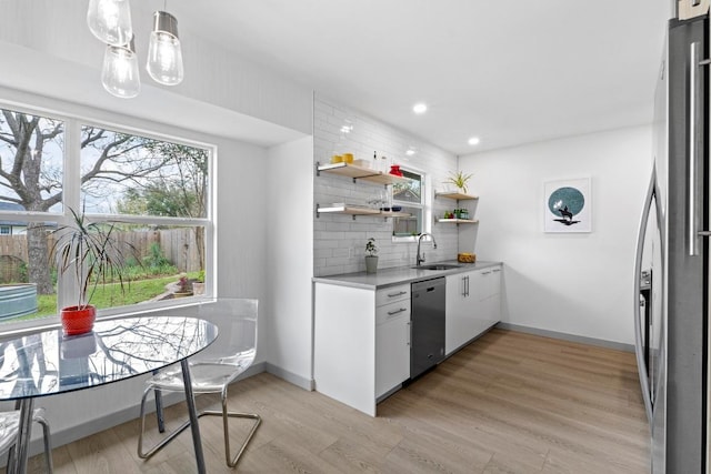 4712 Carsonhill Dr, Austin, TX 78723 - kitchen featuring appliances with stainless steel finishes, decorative backsplash, white cabinets, light countertops, and light wood finished floors
