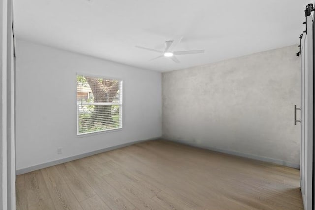 4712 Carsonhill Dr, Austin, TX 78723 - unfurnished room with a barn door, wood finished floors, and a ceiling fan