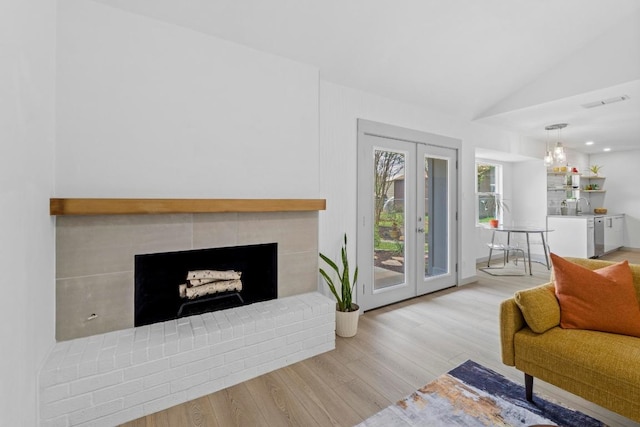 4712 Carsonhill Dr, Austin, TX 78723 - living area with wood finished floors, vaulted ceiling, a fireplace with raised hearth, and french doors