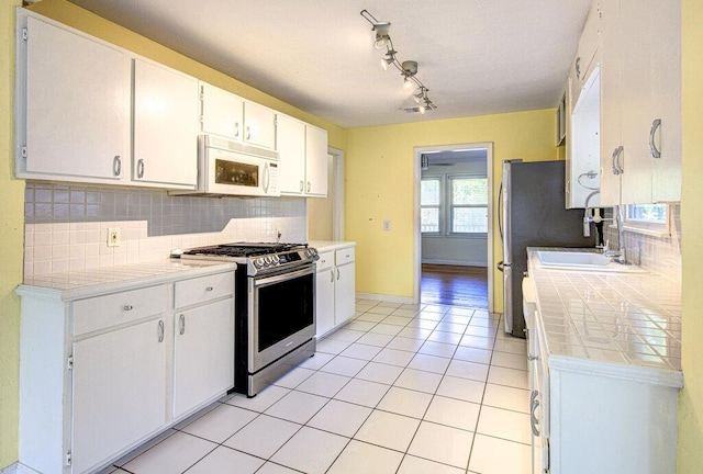 3303 Hollywood Ave, Austin, TX 78722 - kitchen with white microwave, stainless steel gas range, backsplash, white cabinetry, and light tile patterned floors