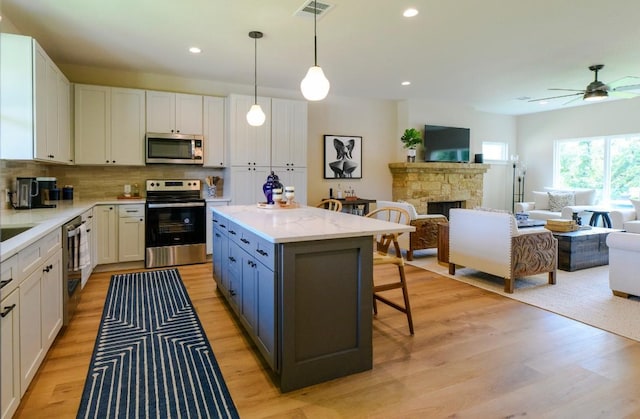 302 Castlehigh Dr, Granite Shoals, TX 78654 - kitchen featuring appliances with stainless steel finishes, open floor plan, a breakfast bar, light wood finished floors, and white cabinetry