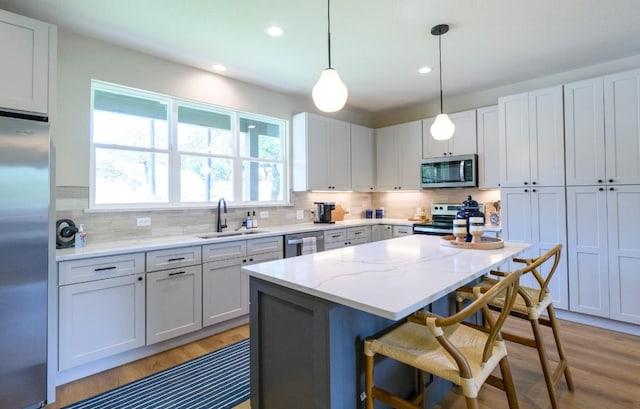 302 Castlehigh Dr, Granite Shoals, TX 78654 - kitchen with appliances with stainless steel finishes, a kitchen bar, light wood finished floors, recessed lighting, and backsplash