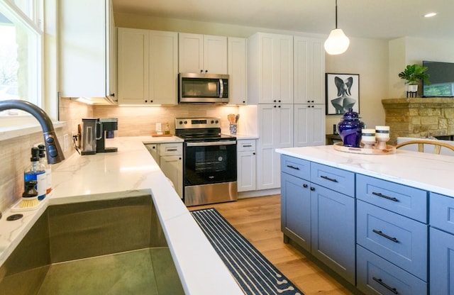 302 Castlehigh Dr, Granite Shoals, TX 78654 - kitchen featuring stainless steel appliances, white cabinetry, tasteful backsplash, light wood-style floors, and light stone countertops