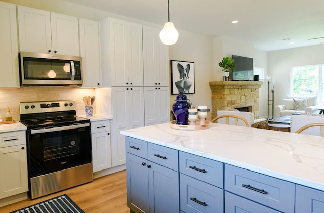 302 Castlehigh Dr, Granite Shoals, TX 78654 - kitchen featuring appliances with stainless steel finishes, open floor plan, light wood finished floors, a stone fireplace, and decorative backsplash
