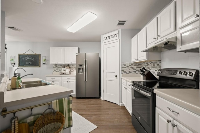 124 Phillips St, Hutto, TX 78634 - kitchen with stainless steel appliances, under cabinet range hood, white cabinetry, backsplash, and dark wood-type flooring