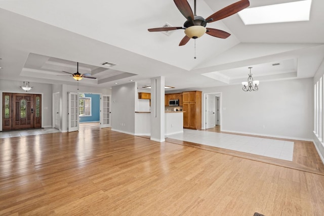 703 Amy Cir, Marble Falls, TX 78654 - unfurnished living room with a raised ceiling, ceiling fan, a chandelier, and light wood-style flooring