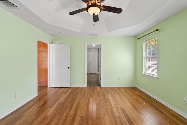 703 Amy Cir, Marble Falls, TX 78654 - unfurnished bedroom with hardwood / wood-style flooring, a tray ceiling, and a ceiling fan